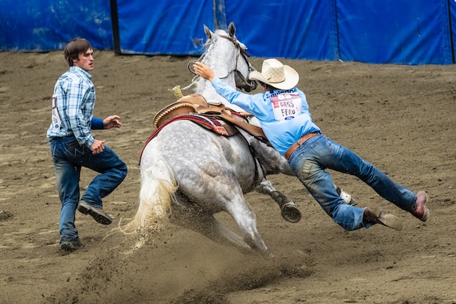 cowboy falling off a horse at a rodeo