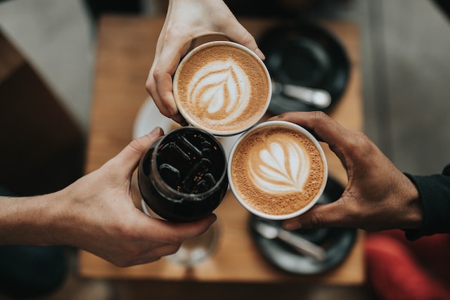 three people toasting their coffee cups
