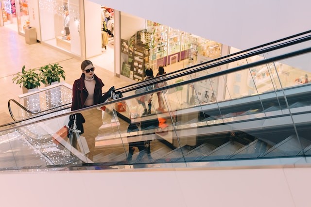 woman riding up an escalator in a mall